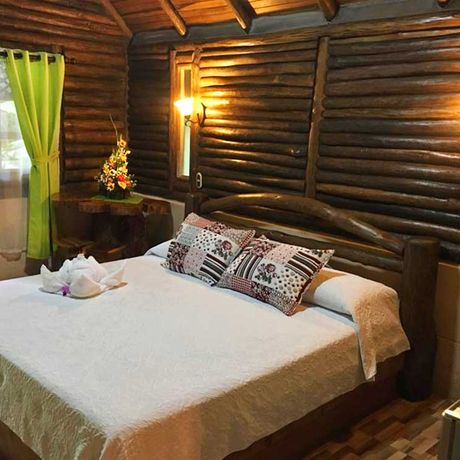 Blick auf ein Bett im Bungalow des Bungalow + Cabinas Arenal Oasis