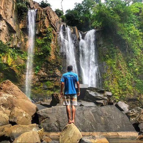 Blick auf einen Mann vor einem Wasserfall beim Tagesausflug Abwechslungsreiche Wasserfall-Tour