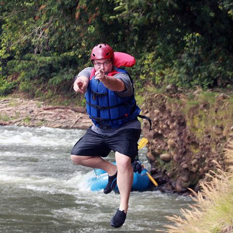 Ein Mann springt mit Anlauf in den Fluss um sich zu erfrischen. 