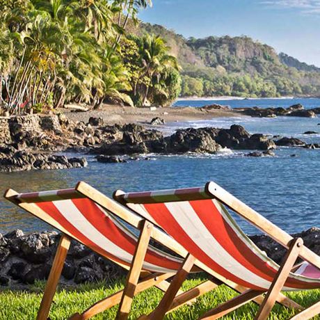 Costa Rica Strandunterkunft Liegestühle Zwei gestreifte Liegestühle im Garten mit Blick auf den Strand