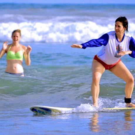 Surfversuche im Meer Blick auf Surfversuche einer Frau im Meer mit applausierender Freundin im Hintergrund
