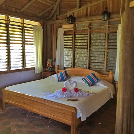 Blick auf ein Bett im Honeymoonbungalow in der Dschungel-Lodge La Cusinga Lodge