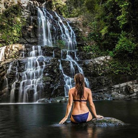 Blick auf eine Frau vor einem Wasserfall beim Tagesausflug Abwechslungsreiche Wasserfall-Tour